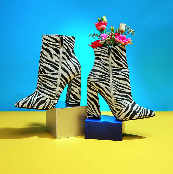 Zebra-print boots with flowers against a blue and yellow background